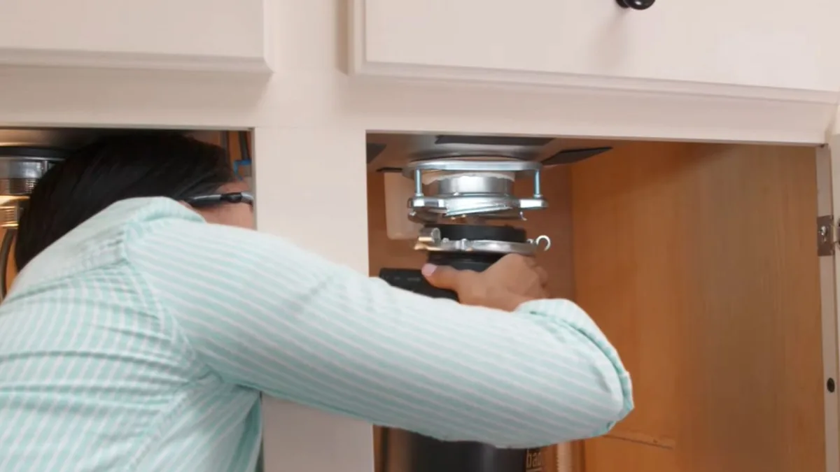 Garbage disposal being installed under a kitchen sink in a Sun City, AZ home